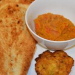 bowl of dhal with nan bread and bhaji on the side