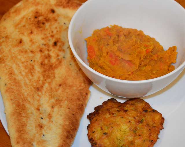 bowl of dhal with nan bread and bhaji on the side