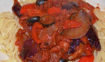 peppers, olives and onions in a tomato sauc eon a bed of penne pasta