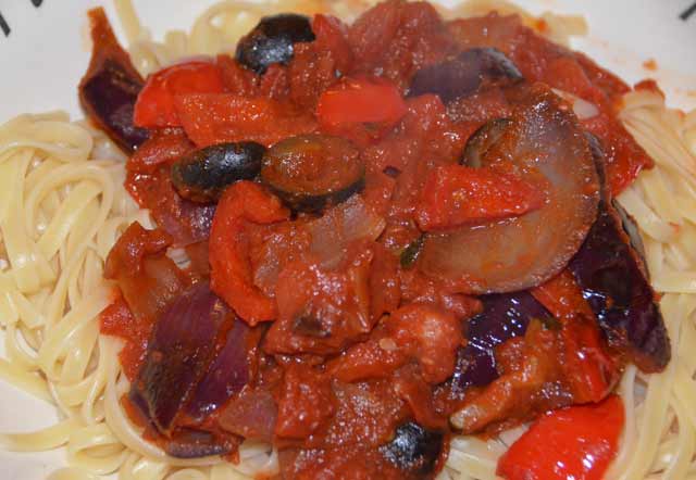 peppers, olives and onions in a tomato sauc eon a bed of penne pasta