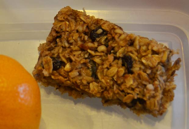 One cereal bar next to an orange