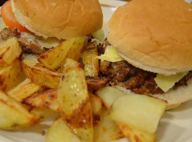 Homemade beefburger in a bun served with potato wedges