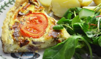 slice of quiche with new potatoes and salad on a plate