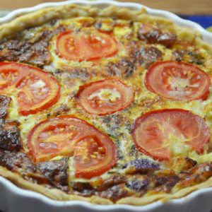 whole quiche in flan with sliced tomatoes on top
