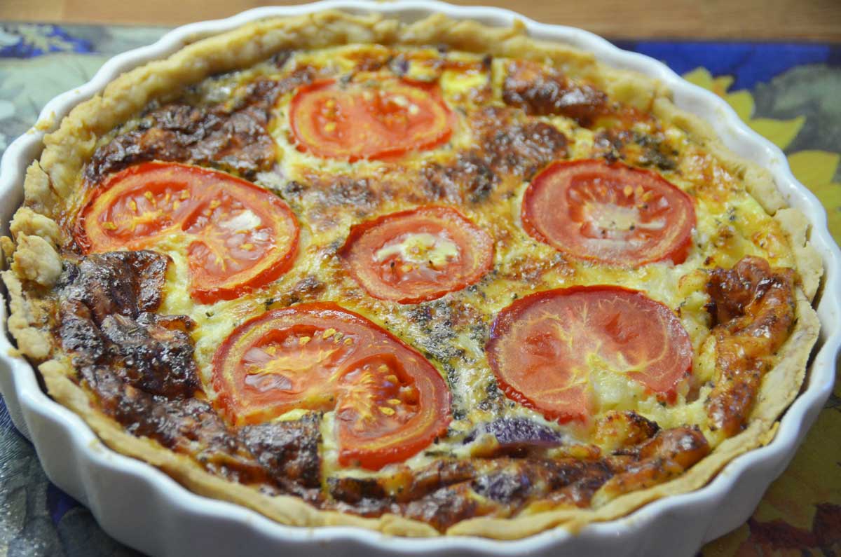 whole quiche in flan with sliced tomatoes on top