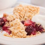 portion of apple and blackberry crumble showing fruit and crumble