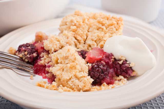 portion of apple and blackberry crumble showing fruit and crumble