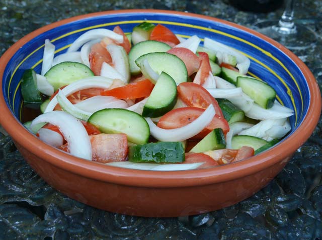 sliced tomatoes, cucumber and onion in a blue stripey dish