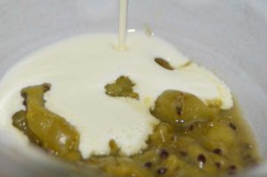 green stewed gooseberries with cream poured over