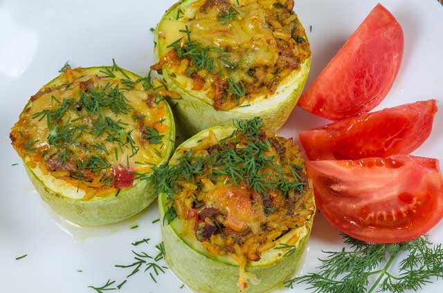 three slices stuffed marrow on plate with tomato wedges