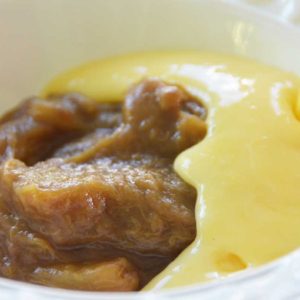 stewed rhubarb with yellow custard being poured on