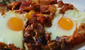 serving of two eggs in tomato and pepper sauce on a plate