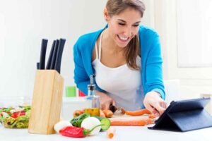 woman looking at tablet whilst cooking in kitchen