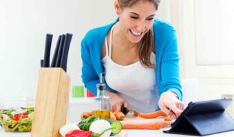 woman looking at tablet whilst cooking in kitchen