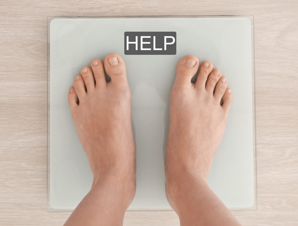 Weight loss concept. Woman standing on scales. Word HELP on screen
