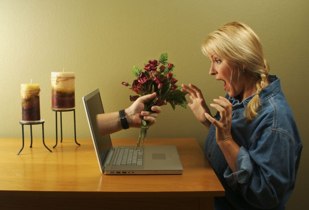 woman looking at laptp and flowers being offered through the screen