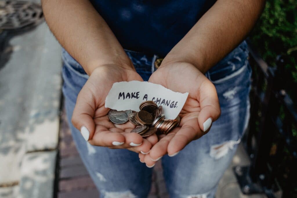 woman holding coins in her hands and a note saying make a change