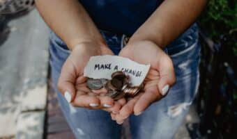 woman holding coins in her hands and a note saying make a change